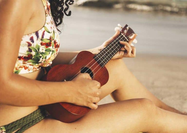 mujer tocando ukelele playa