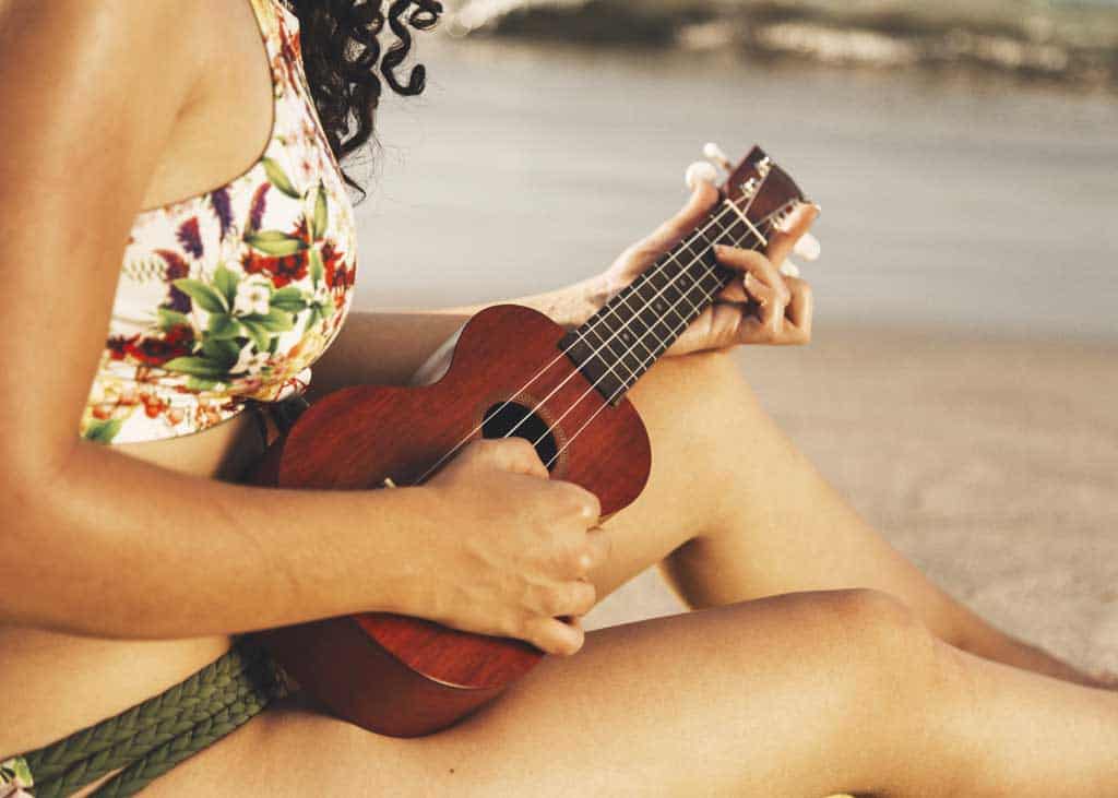 mujer tocando ukelele playa