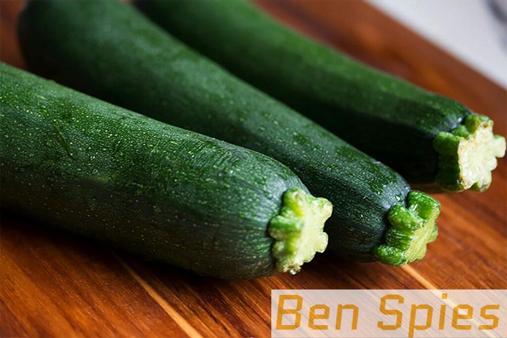 Close-up of three fresh green zucchinis on a wooden surface, perfect for food themes.