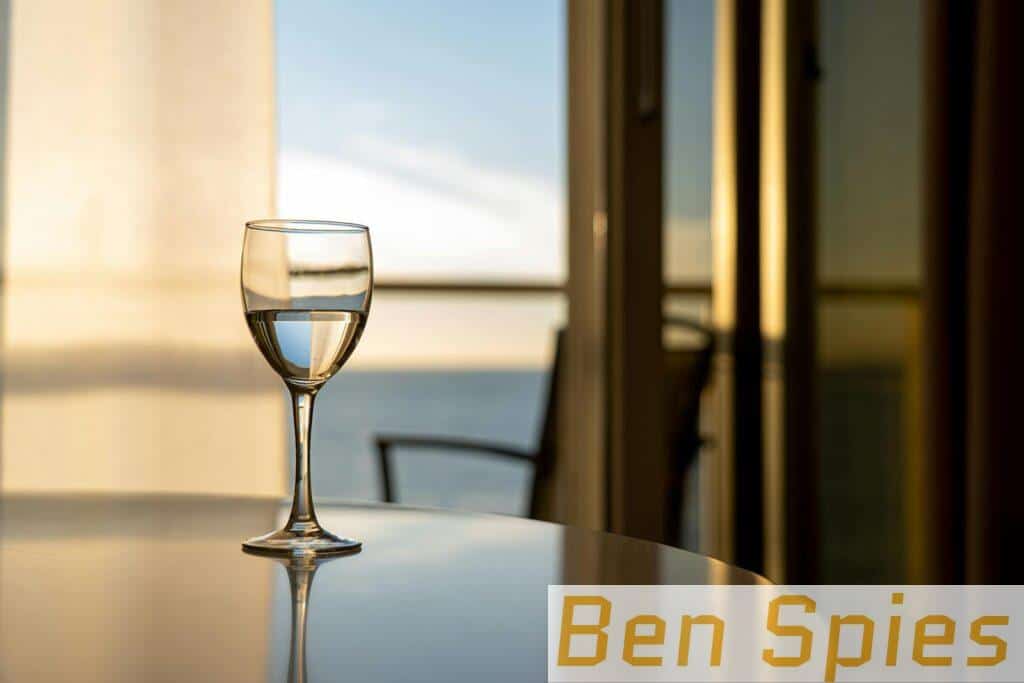 A glass of wine on a table with a stunning ocean view through a window, captured indoors.
