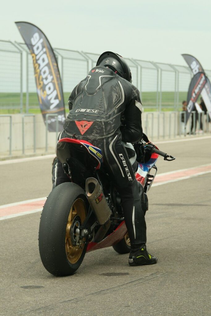 Piloto con equipo completo sobre una moto en un circuito