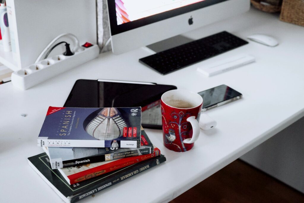 Taza roja y blanca junto a un ordenador sobre una mesa de trabajo